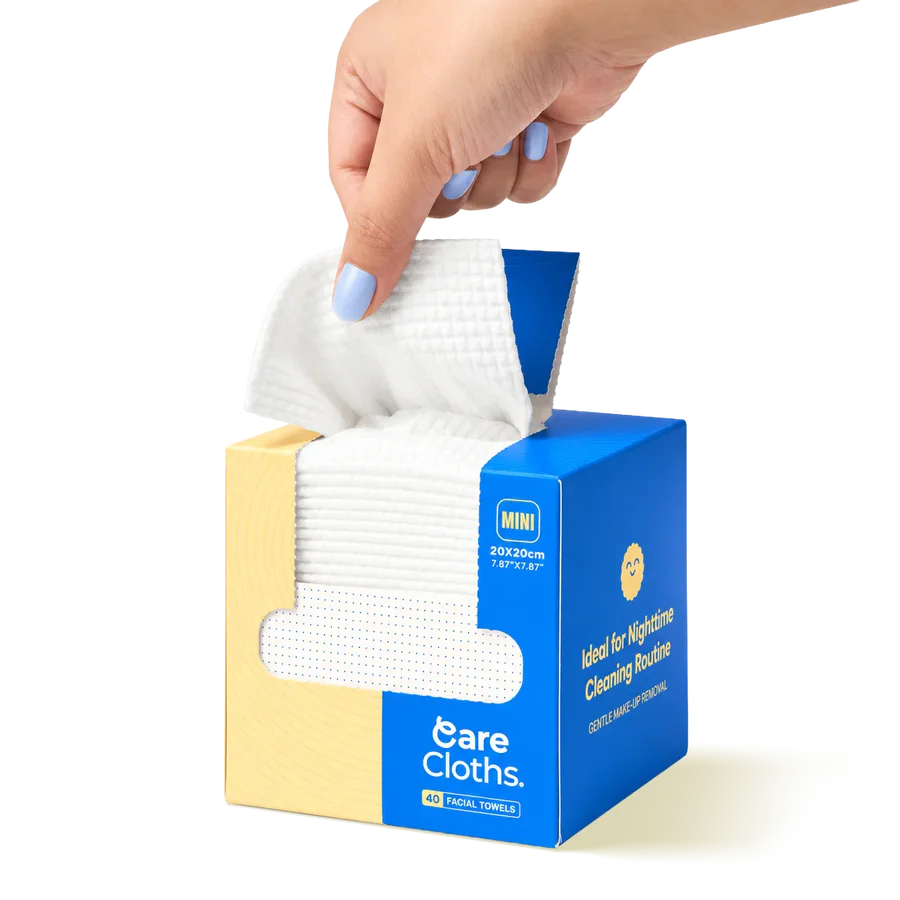 Open CareCloths MINI box showing the stack of 40 facial towels, a hand pulling one out